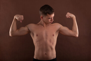 Handsome muscular shirtless adolescent boy flexing muscles.