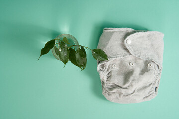 Washable ecological fabric cotton diapers on a light green background. A twig of a tree with leaves...