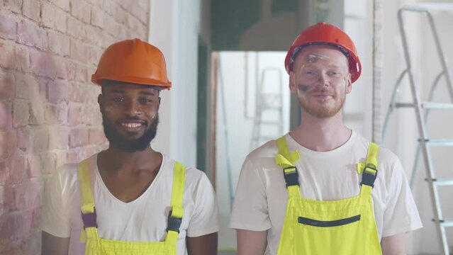 Portrait of multiethnic builders in uniform smiling at camera. Realtime