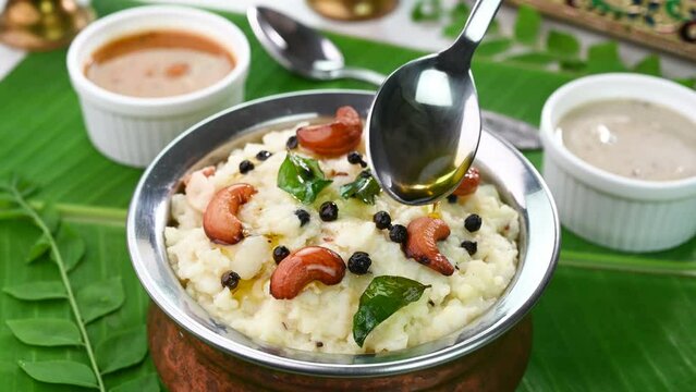 Pouring ghee on top of ven pongal, famous south indian breakfast.