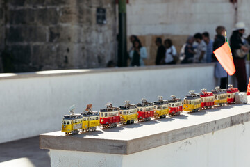 Typical gifts in form of trams on tourist street in Lisbon Portugal against background of blurred...