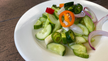 Close up of sauce for pork satay, pickles which are cucumber slices and onions in vinegar, serving on white plate
