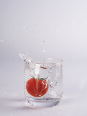 Tomate fällt in Wasserglas