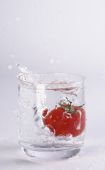 Tomate fällt in Wasserglas