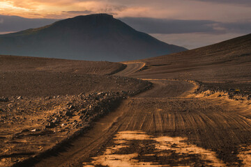 Fototapeta premium Dirt road and volcanic mountain to Landmannalaugar among remote wilderness in the evening at Icelandic Highlands
