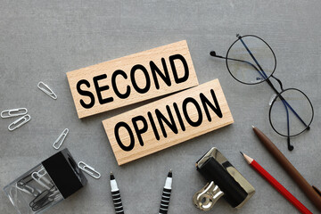 Second opinionblack font on wooden blocks. Gray background.