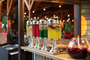 Glass jars with refreshing lemonade at summer party, cocktail bar. Soft selective focus. Big glass jars with tap filled with fresh cold drinks served in bar. Event with catering. Sangria cocktail	