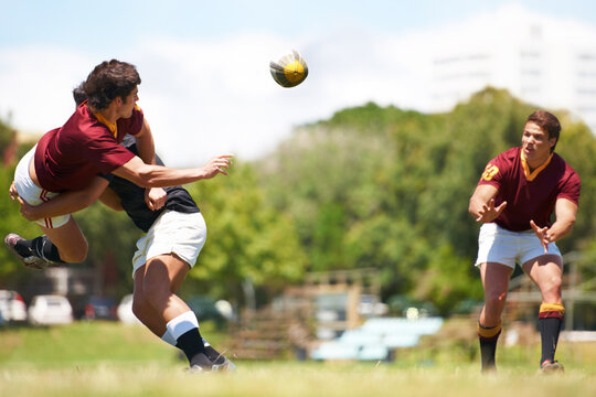 Working together for stronger unity. Shot of a young rugby player executing a pass mid-tackle.