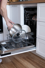 Women's hands sort clean dishes from the dishwasher