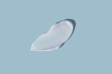 White smear of cosmetic cream on a blue background. Creamy foundation texture isolated. Smear of face cream. Close up of cream texture.