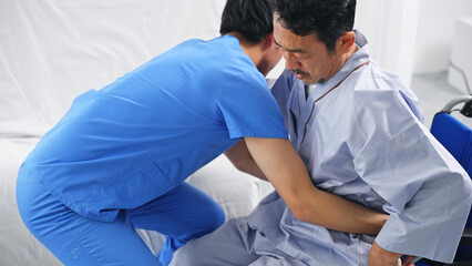 Obraz premium ベッドから車椅子へ移乗介助する介護士