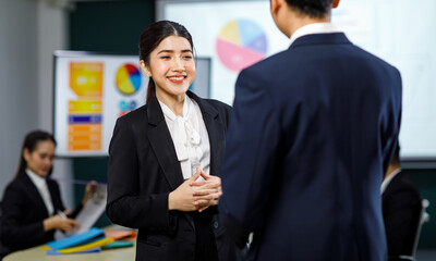 Fototapeta na wymiar Millennial Asian professional successful male businessman manager female businesswoman employee in formal business suit standing discussing brainstorming working together in meeting room