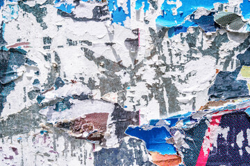 Torn paper collage background on an old poster on a street wall. Texture and surface of torn paper.