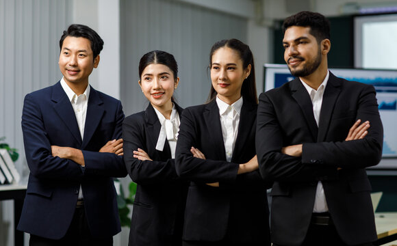 Millennial Asian professional successful female businesswomen Indian multinational male businessmen in formal business suit standing side by side crossed arms posing taking photo together in company