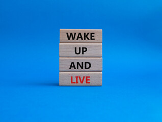 Wake up and live symbol. Wooden blocks with words Wake up and live. Beautiful blue background....