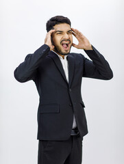 Portrait studio shot Millennial Asian Indian stressed depressed upset professional bearded male businessman in formal business suit holding hands on head having headache shouting on white background
