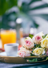 Bouquet of roses and breakfast in bed on a golden tray