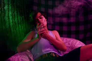 Stoned guy with glitter makeup lighting cigarette