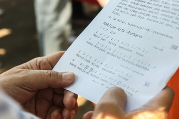 Someone is reading song texts and readings for Catholic worship in Indonesian.