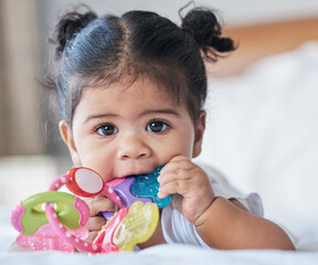 Portrait, baby girl and biting toys in bedroom, house and home for development, growth and teething progress. Cute kid, face and chewing rattle in mouth for tooth, child and playing in nursery room - obrazy, fototapety, plakaty