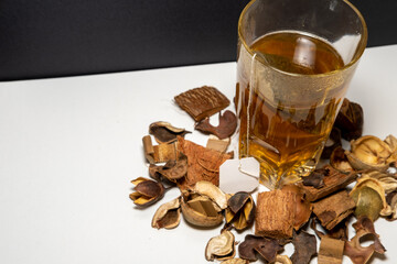 Infusión caliente de manzanilla en un vaso de cristal con flores secas alrededor y un segundo...