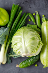 Background of organic green raw vegetables on black table. Top view of healthy organic food.