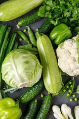 Background of organic green raw vegetables on black table. Top view of healthy organic food.