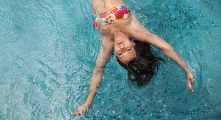 top view to young sexy brunette colorful bikini woman swimming in turquoise pool spa water