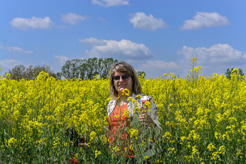 Fototapeta premium portrait of woman in a field of yellow flowers. Horizontal. With copy space.