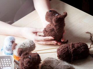A knitted toy in the hands of a young woman. Knitting concept , handmade, an activity for the soul and mental health.