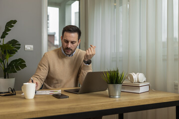 Young man using laptop computer for e-learning or paying bills online