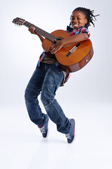 Moved by the music. A happy young African-American boy playing a guitar while balancing on his toes.