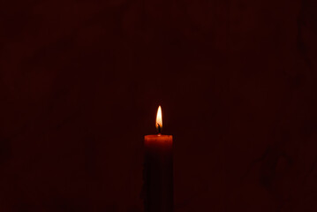 Old lighting a candle in the dark.Close up single candle light and flame on black background. Melted Wax Candle light border design. Burning at Night, Darkness.Candlelight.Copy space.