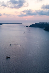 Sunset seen from the top of the island of Santorini with sailing banks in the sea.
