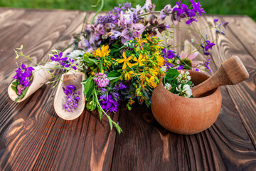 Summer medicinal herbs - St. John's wort, chamomile, clover near wooden mortar. Preparation of...