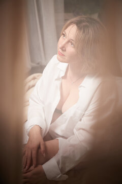 Portrait of sexual body positive adult lady woman in an intimate in tender space indoors in a bedroom. Plump girl poses in black underwear and white shirt during boudoir style photo shoot