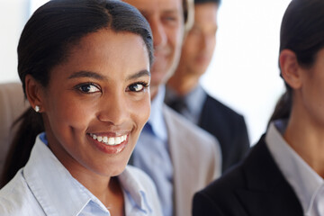 Feeling the need to succeed. Portrait of a young African woman smiling with her coworkers in the background.
