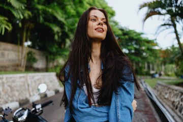 Portrait of woman brunette smile with teeth running down the street against backdrop palm trees in the tropics, summer vacations and outdoor recreation, the carefree lifestyle of a freelance student.