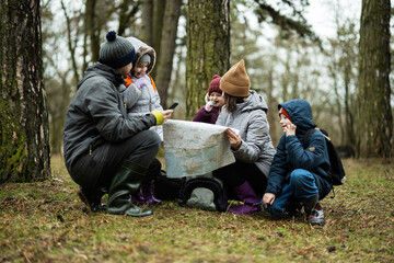 Family and kids with map in the forest.