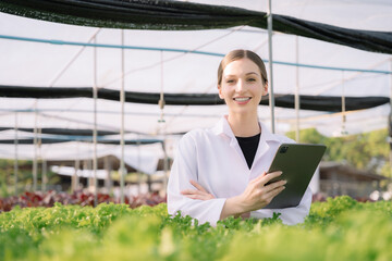 Smiling female geneticists, biologists, and scientists  working in Hydroponics greenhouse farm...