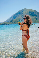 Cheerful bikini woman enjoying summer sea holding fresh cocktail with drinking straw