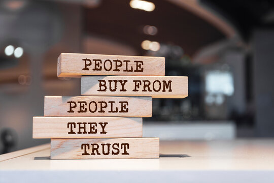 Wooden blocks with words 'People Buy From People They Trust'.