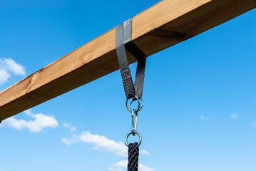 Obraz premium A modern cubic playground made of wooden logs and metal corners, visible nylon ropes and clip hook.