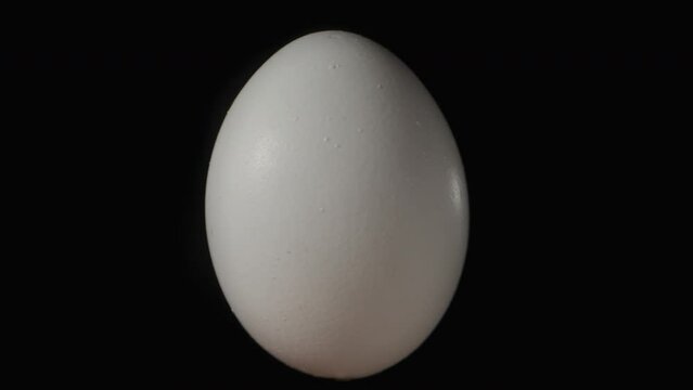A white chicken egg rotates on a black background. Isolate close-up.
