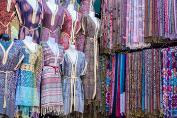 typical moroccan clothes on display in a shop in a souk in marrakech.