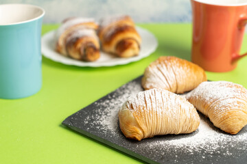 Delicious sweets of European cuisine: Sfogliatella and chocolate croissant with cups of coffee on a colored background. High quality photo