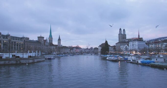 Wide shot of Zurich historic city center landmark with The Grossmunster (great minster) protestant church and the Limmat river at night, Switzerland. Swiss travel destination cityscape. slow motion.