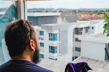 At home, clean the glass balcony. A man of Asian origin is cleaning his home.