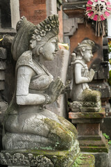 Stone statue with hands in a praying atthe temple' entrance on Bali, Indonesia.