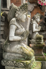Stone statue with hands in a praying atthe temple' entrance on Bali, Indonesia.